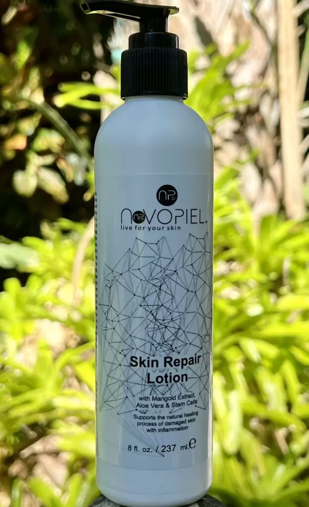 Skin Repair Lotion bottle against a blurred green background. Features ingredients like marigold extract and aloe vera for healing skin.